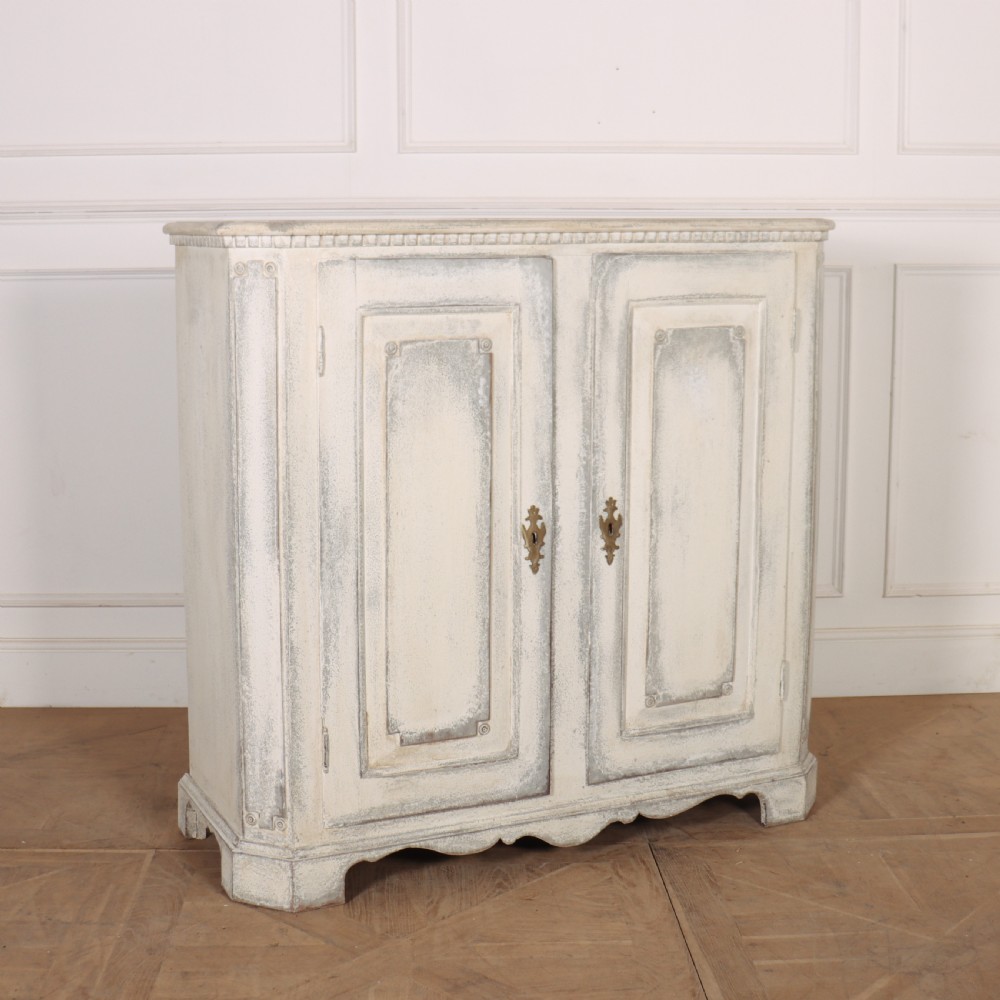 An 18th-century Swedish painted wooden linen cupboard featuring panelled double doors, brass keyhole escutcheons, and a distressed off-white painted finish. View VII