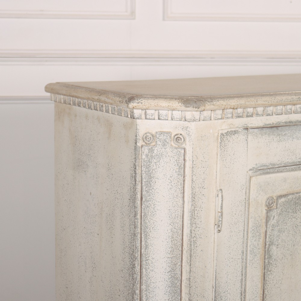 An 18th-century Swedish painted wooden linen cupboard featuring panelled double doors, brass keyhole escutcheons, and a distressed off-white painted finish. View VIII