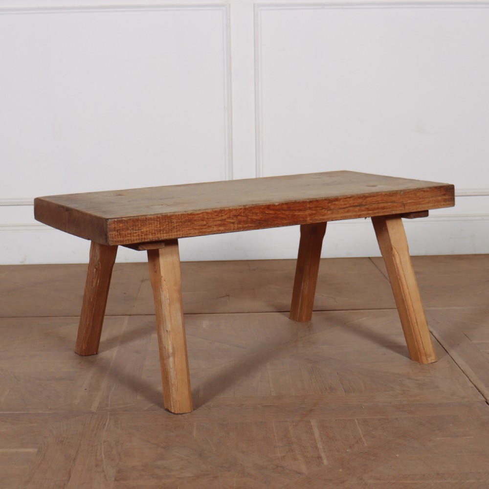 A low French primitive rectangular coffee table made of rustic warm brown timber with splayed tapered legs.