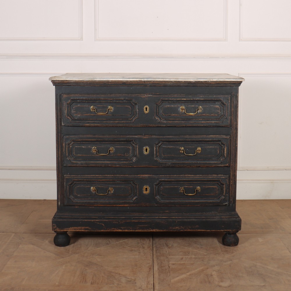 An 18th-century French painted black commode featuring three long drawers with moulded panels, brass drop handles, and a grey marble top. View II