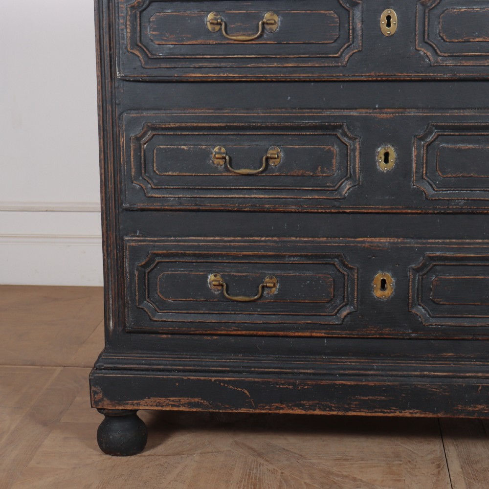 An 18th-century French painted black commode featuring three long drawers with moulded panels, brass drop handles, and a grey marble top. View VIII