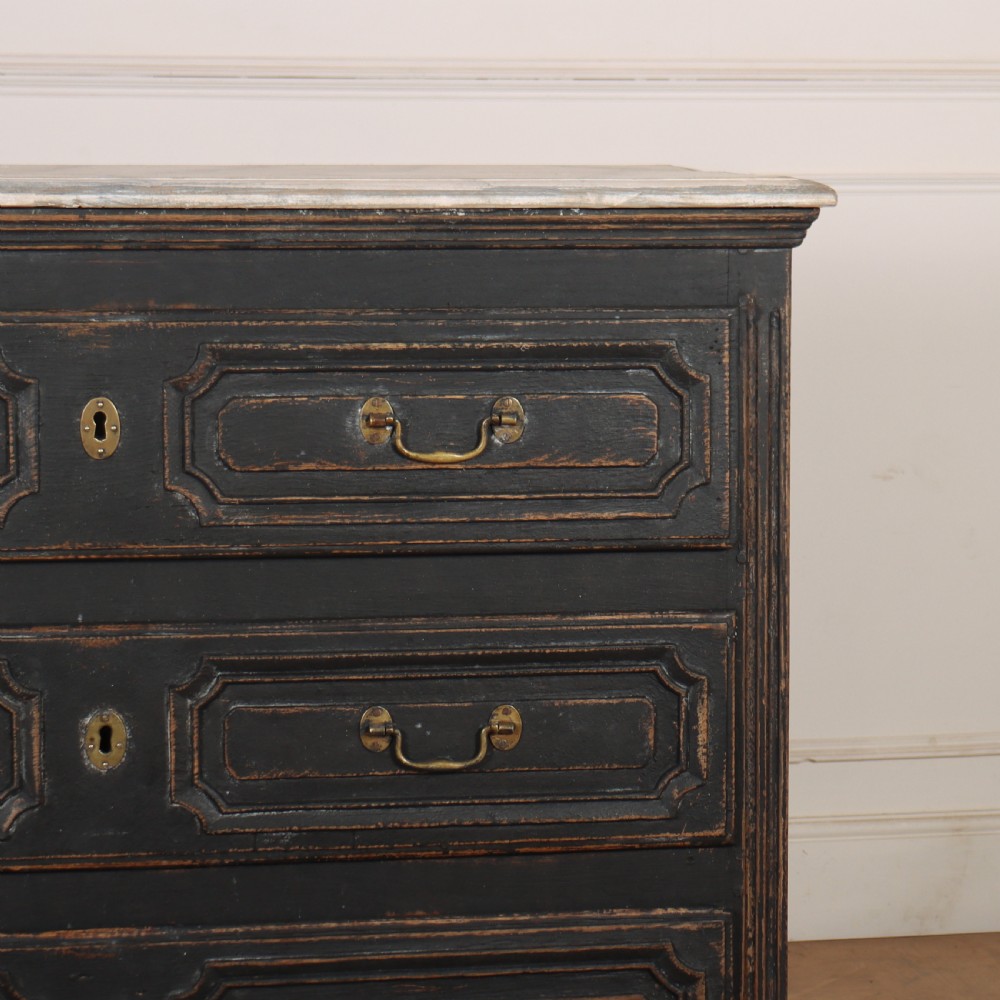 An 18th-century French painted black commode featuring three long drawers with moulded panels, brass drop handles, and a grey marble top. View IX