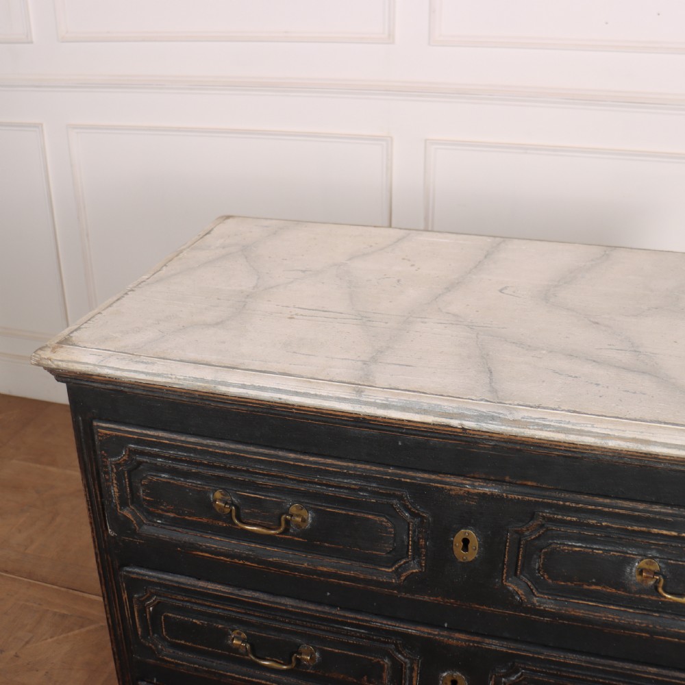 An 18th-century French painted black commode featuring three long drawers with moulded panels, brass drop handles, and a grey marble top. View X