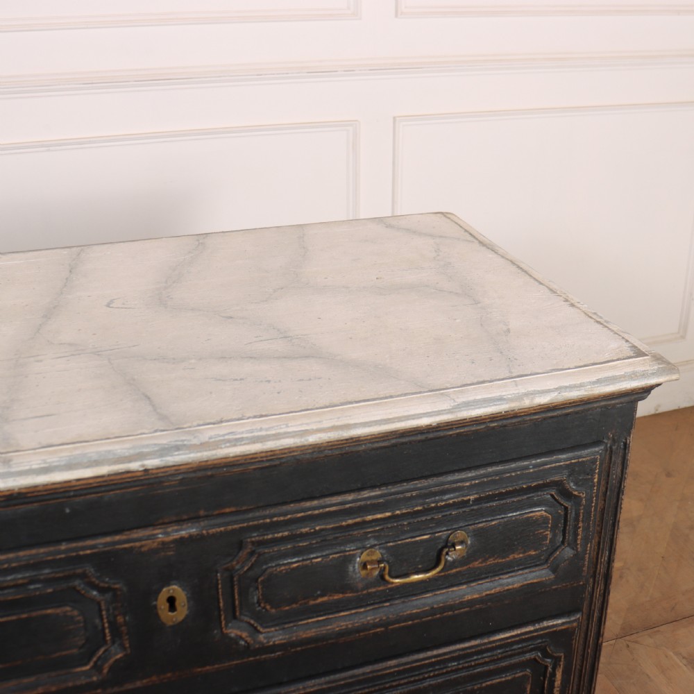An 18th-century French painted black commode featuring three long drawers with moulded panels, brass drop handles, and a grey marble top. View XI