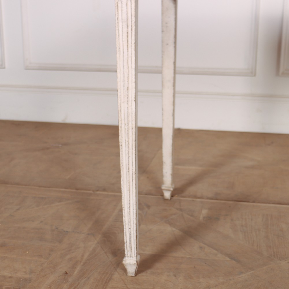 An off-white painted Swedish Gustavian side table featuring slim fluted legs, carved corner rosettes, and a single frieze drawer with a brass pull knob. View III