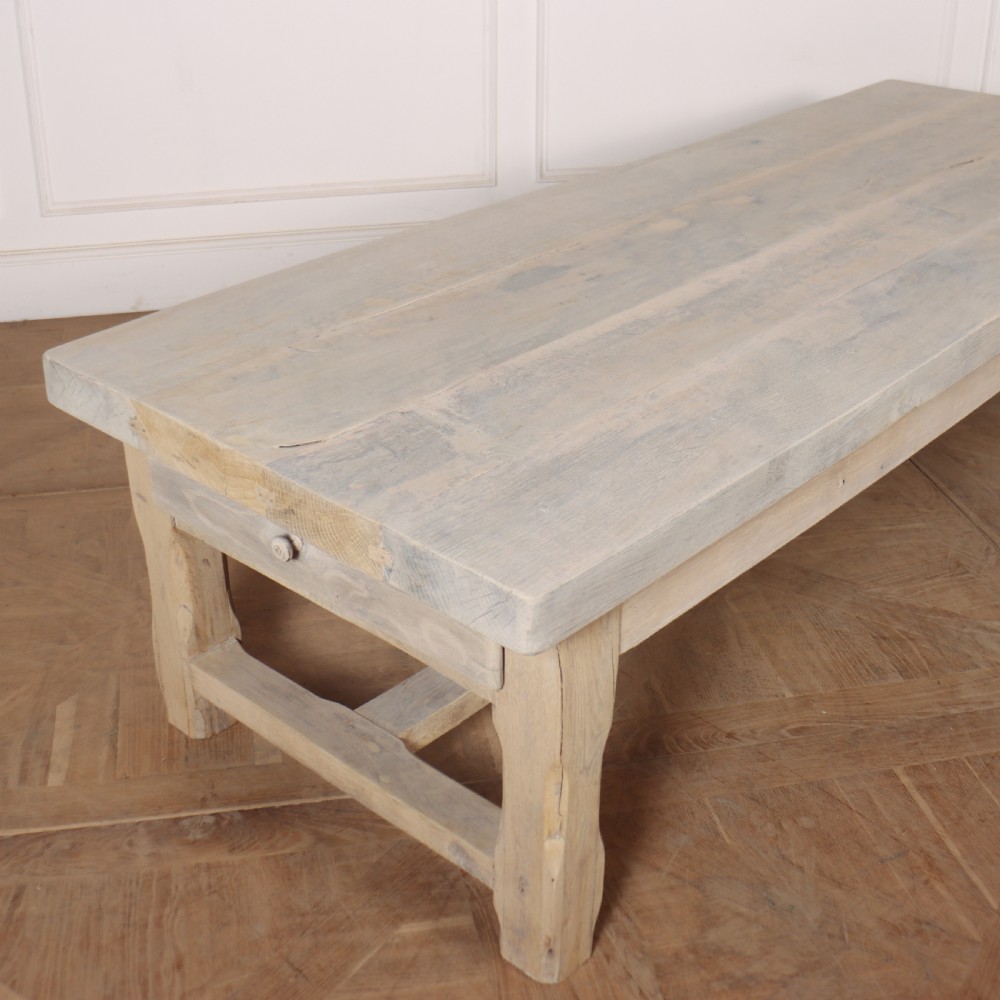 A low rectangular French coffee table constructed from bleached oak, featuring a thick plank top, square legs, a low stretcher, and a small end drawer. View V