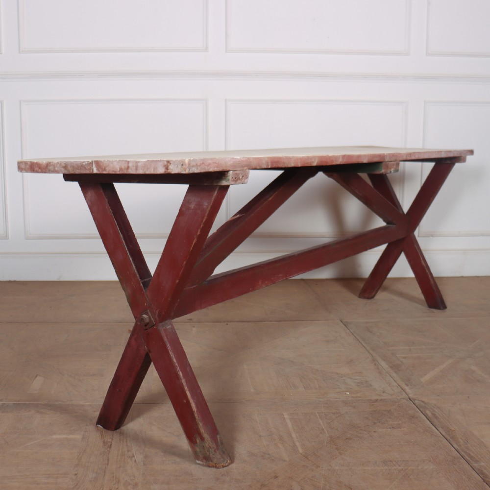 A long wooden tavern table featuring a light scrubbed timber top supported by a red painted X-frame trestle base. View III