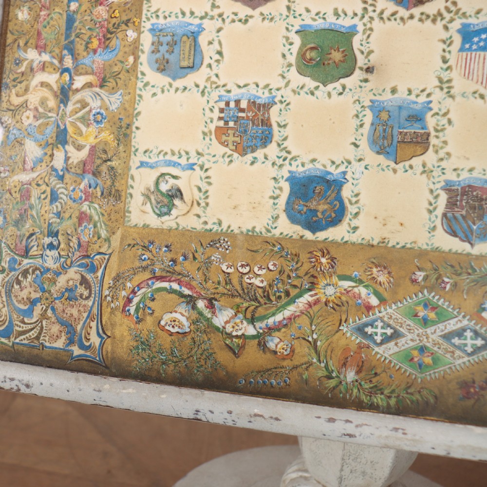 A square painted lamp table featuring a grid of heraldic coats of arms on a cream ground, supported by a carved off-white pedestal base. View VII