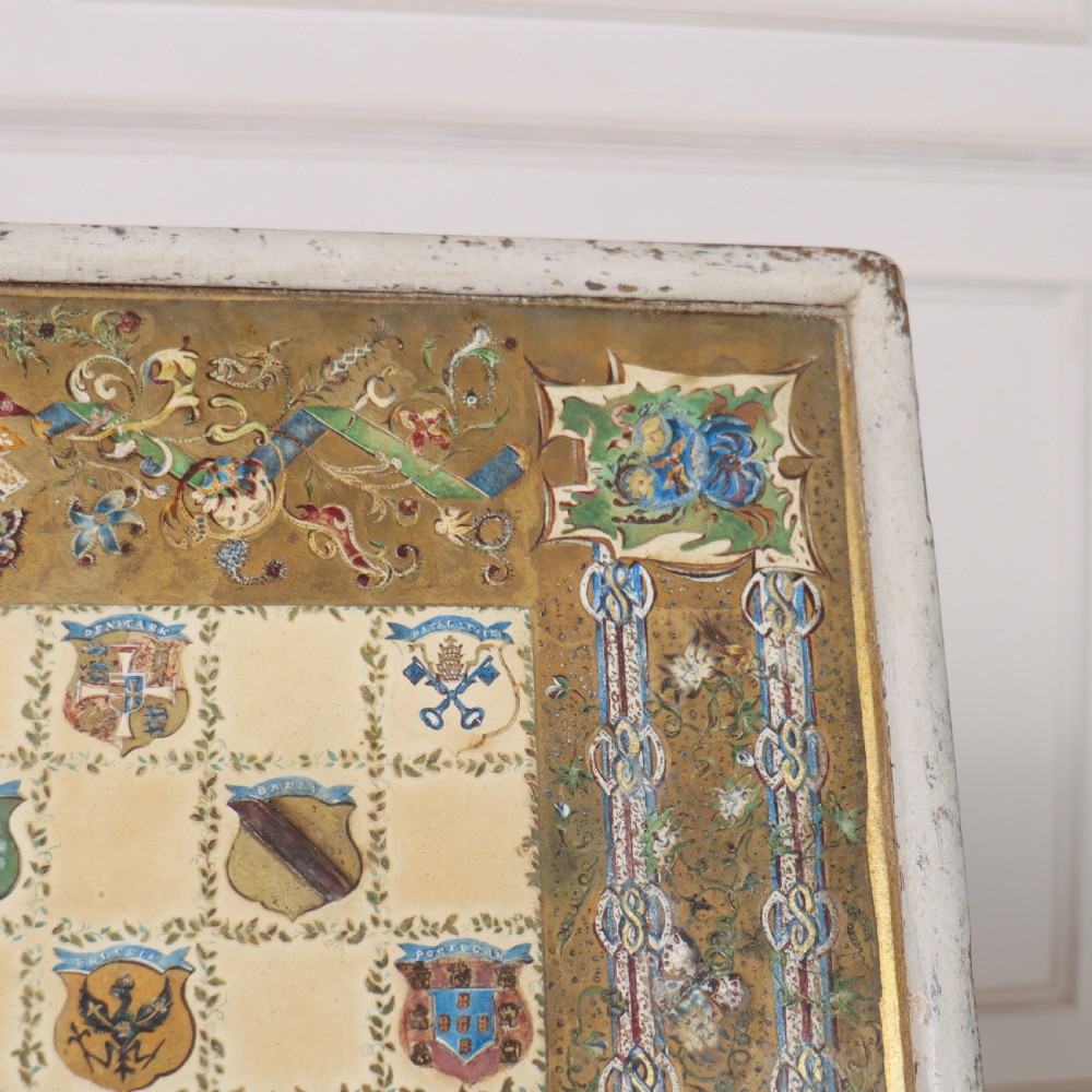A square painted lamp table featuring a grid of heraldic coats of arms on a cream ground, supported by a carved off-white pedestal base. View VIII
