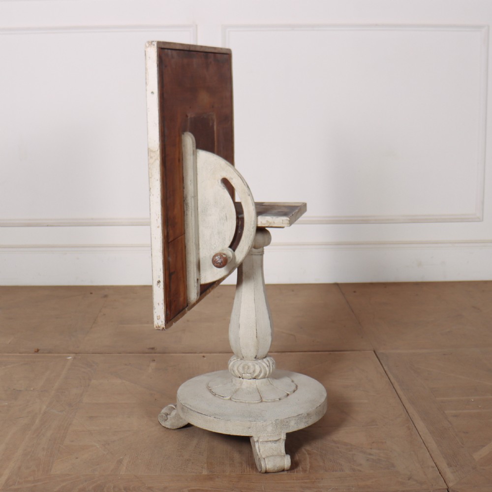 A square painted lamp table featuring a grid of heraldic coats of arms on a cream ground, supported by a carved off-white pedestal base. View IX