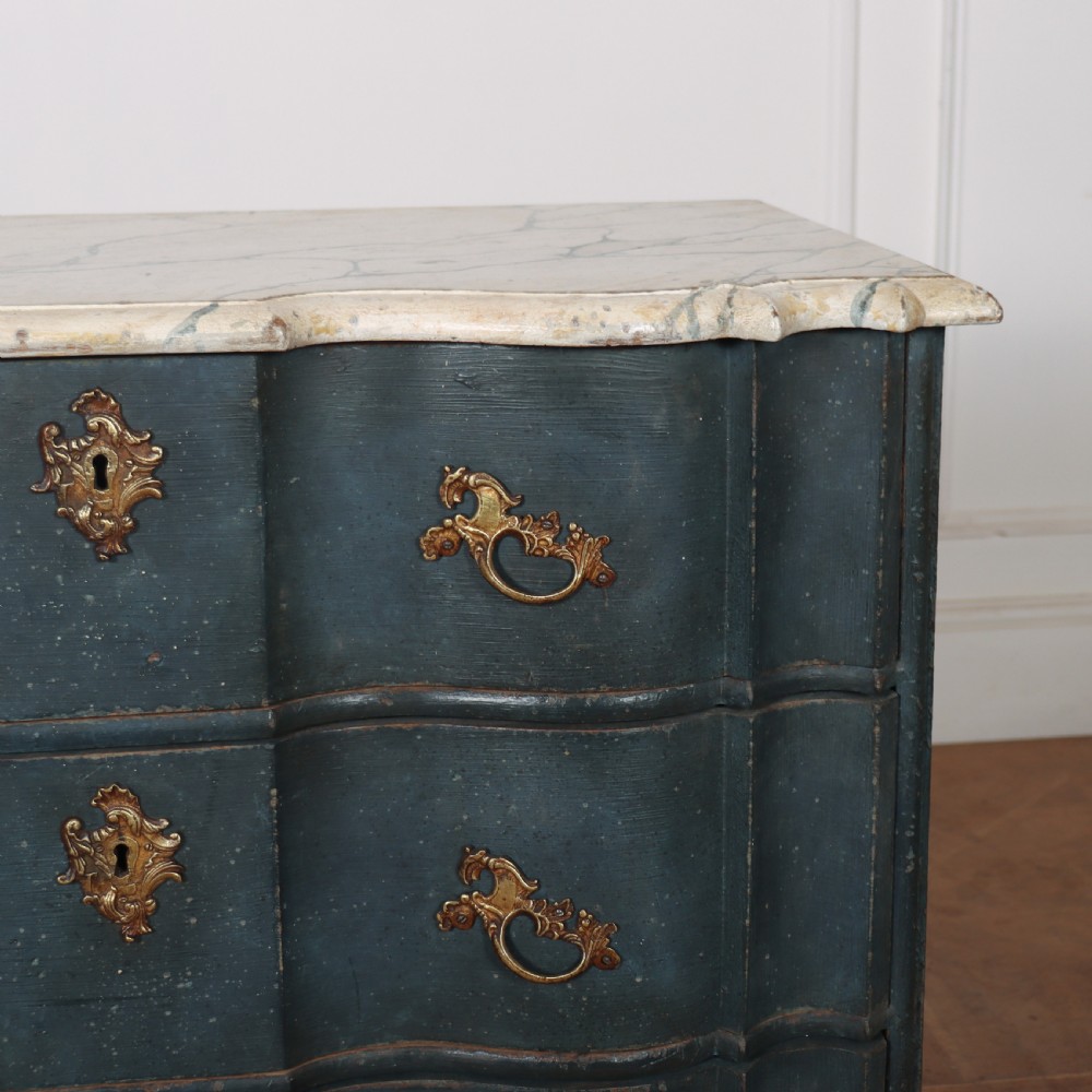 An 18th-century Dutch painted commode featuring a blue serpentine-front wooden body, three drawers with ornamental brass handles, and a contoured white marble top. View III