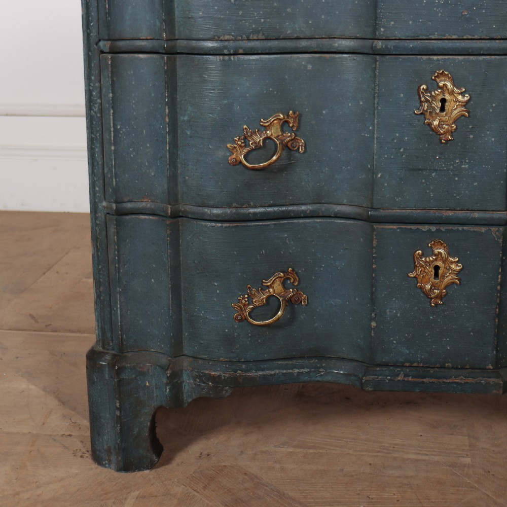 An 18th-century Dutch painted commode featuring a blue serpentine-front wooden body, three drawers with ornamental brass handles, and a contoured white marble top. View VII