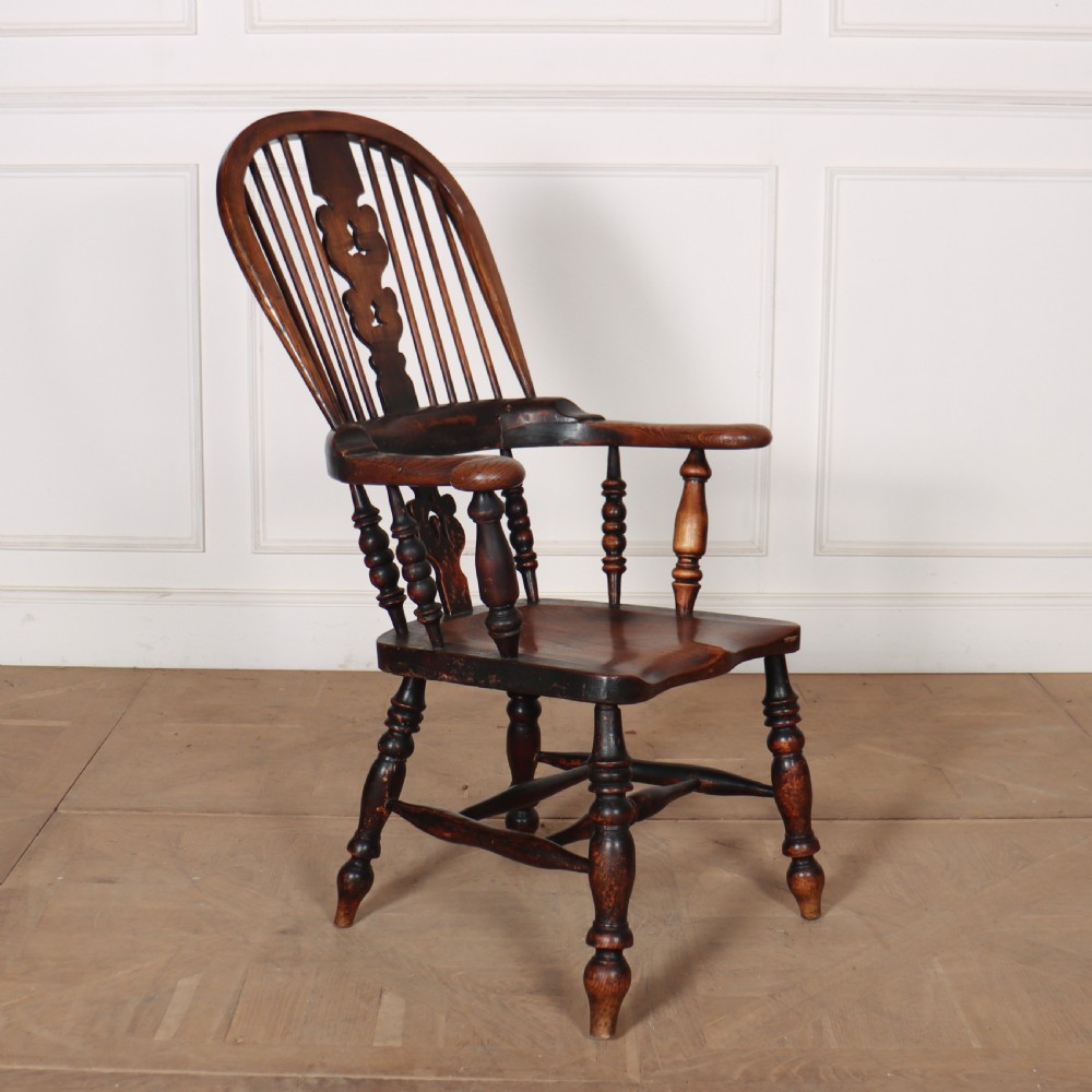 An antique dark wood Yorkshire Windsor armchair featuring a hoop back with a central pierced splat, slender spindles, broad armrests, and turned legs. View II
