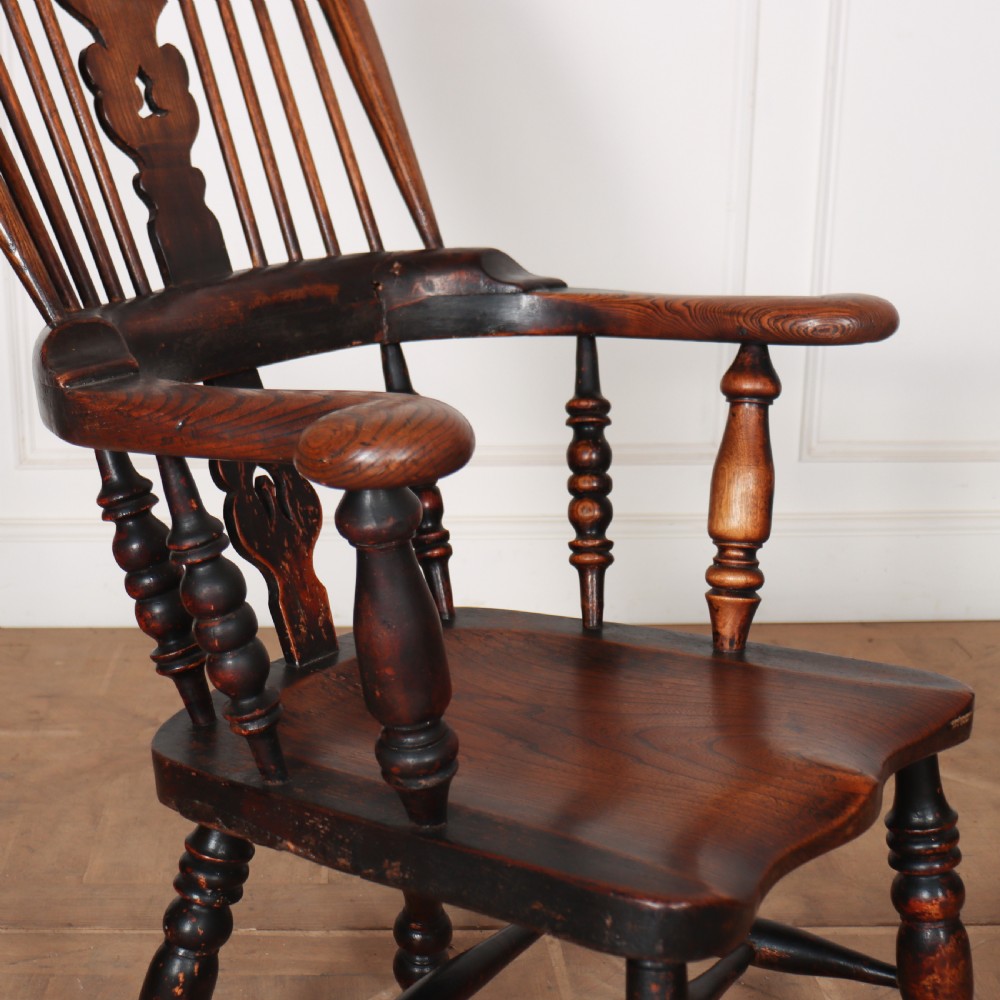 An antique dark wood Yorkshire Windsor armchair featuring a hoop back with a central pierced splat, slender spindles, broad armrests, and turned legs. View III