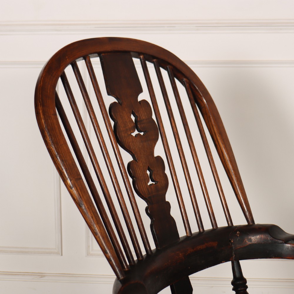 An antique dark wood Yorkshire Windsor armchair featuring a hoop back with a central pierced splat, slender spindles, broad armrests, and turned legs. View IV