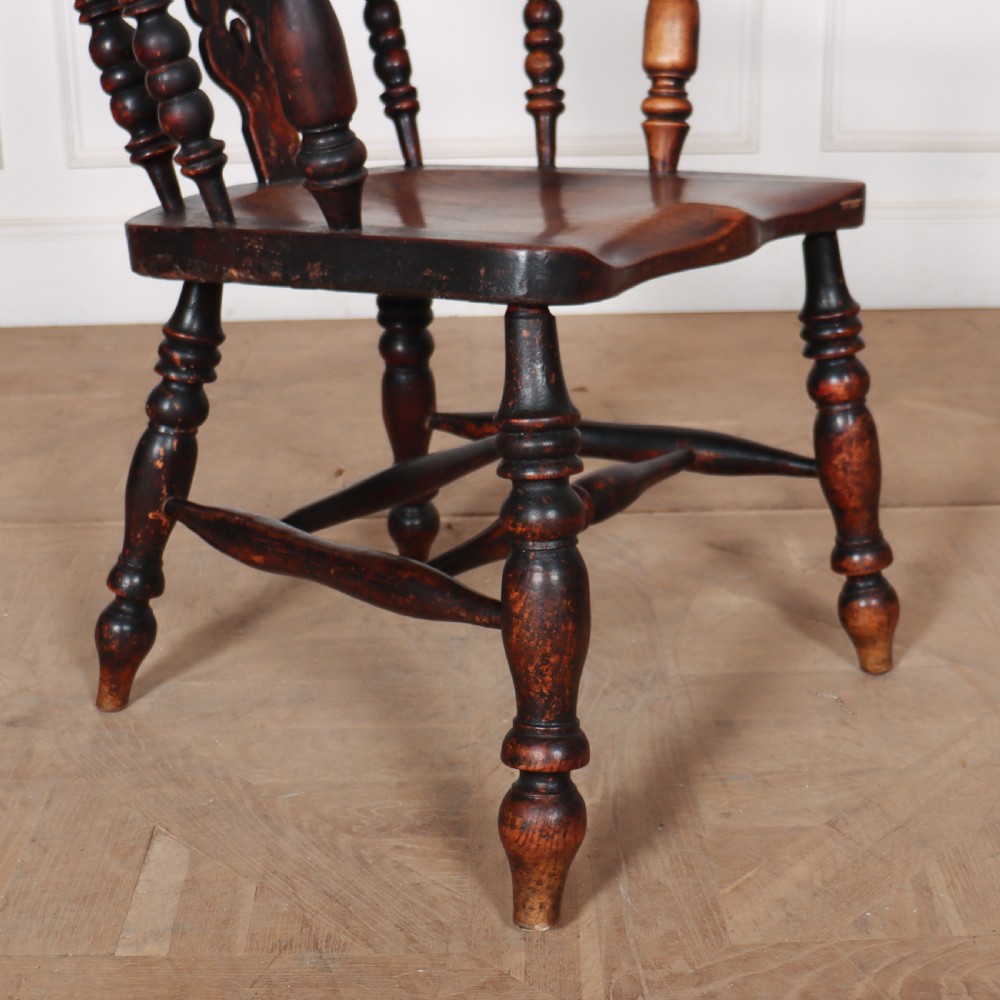 An antique dark wood Yorkshire Windsor armchair featuring a hoop back with a central pierced splat, slender spindles, broad armrests, and turned legs. View V