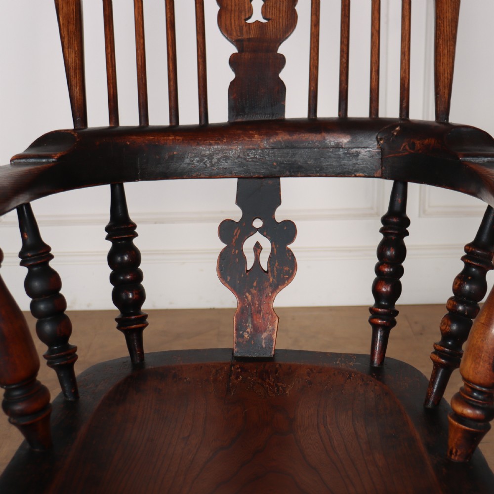 An antique dark wood Yorkshire Windsor armchair featuring a hoop back with a central pierced splat, slender spindles, broad armrests, and turned legs. View VI