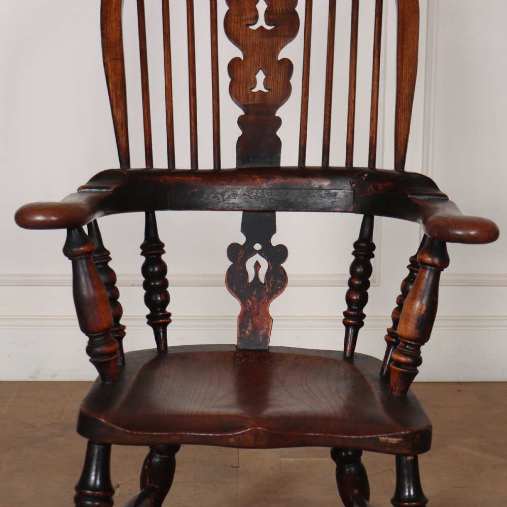 An antique dark wood Yorkshire Windsor armchair featuring a hoop back with a central pierced splat, slender spindles, broad armrests, and turned legs. View VII