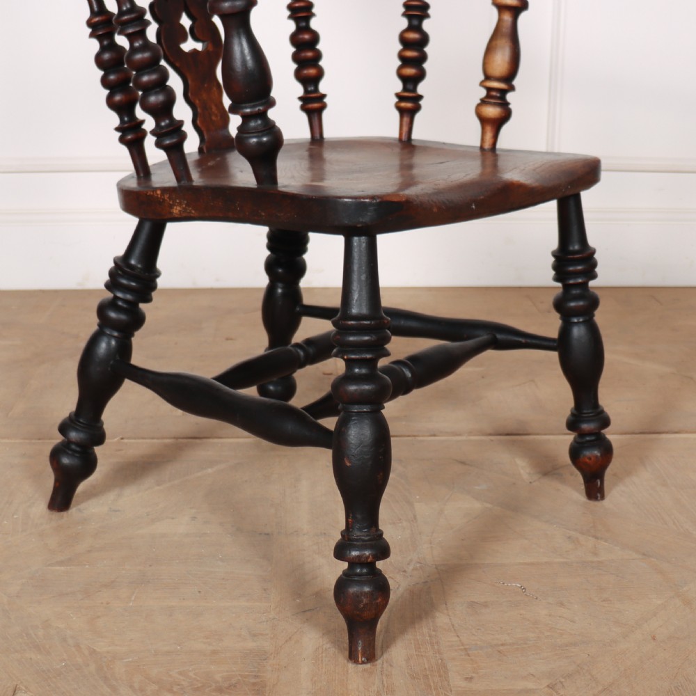 A 19th-century dark brown wood Yorkshire Windsor armchair featuring a hoop back, pierced central splat, turned legs, and curved armrests. View V