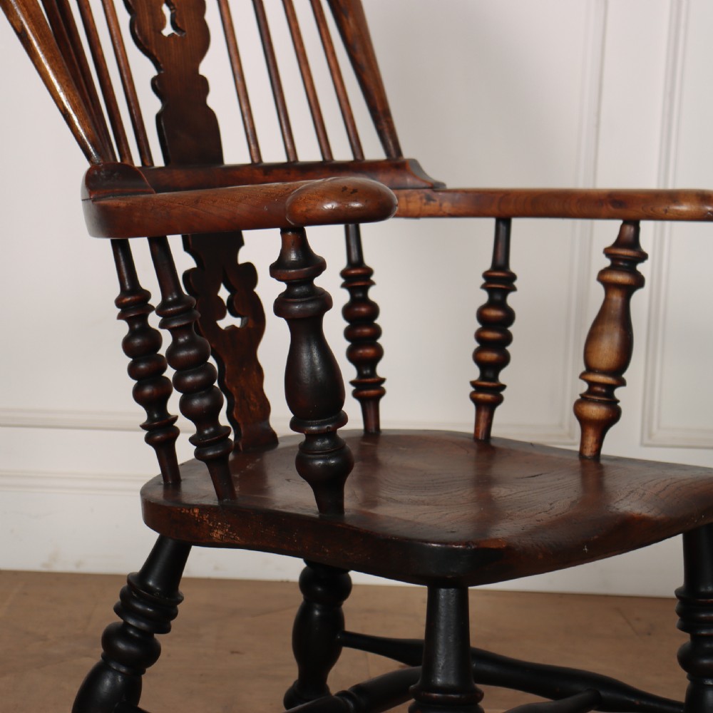 A 19th-century dark brown wood Yorkshire Windsor armchair featuring a hoop back, pierced central splat, turned legs, and curved armrests. View VI