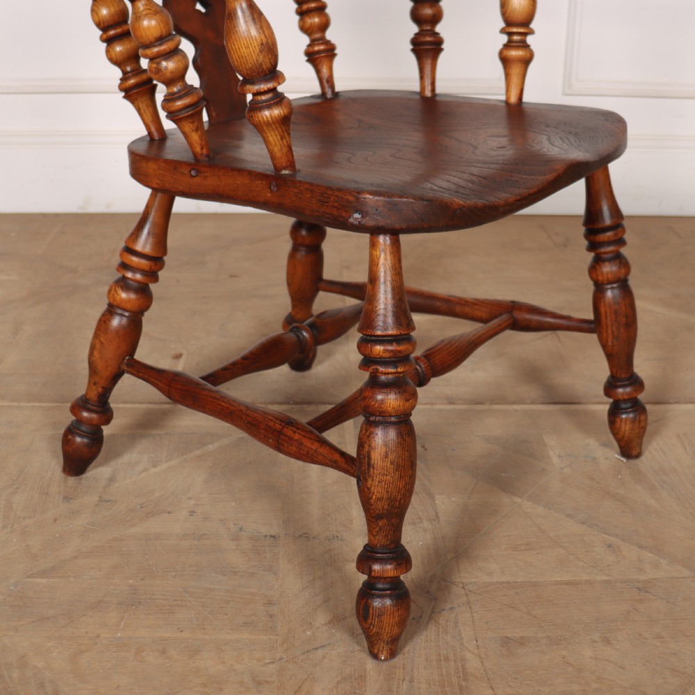 A warm brown wooden Windsor armchair featuring a hoop back, pierced central splat, turned spindles, a contoured seat, and turned legs with stretchers. View VI