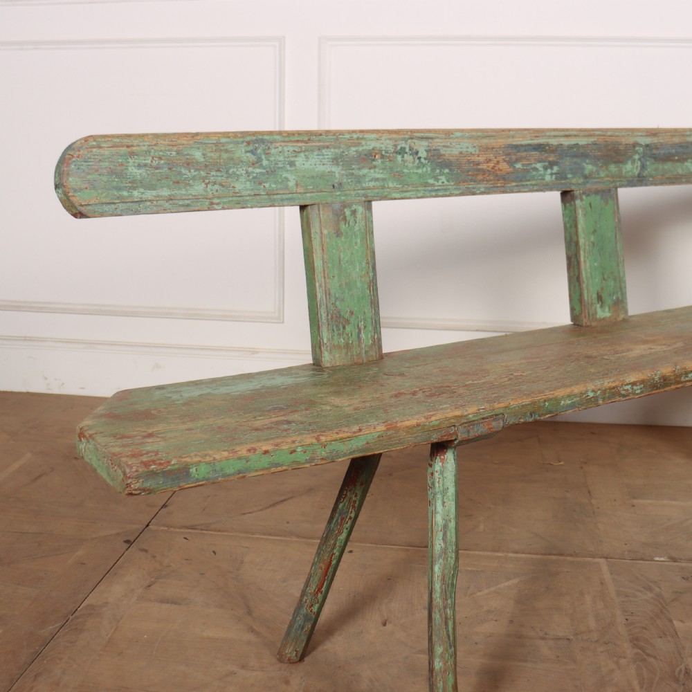 A long rustic wooden bench featuring distressed green paintwork, a simple narrow backrest, and four splayed legs. View II
