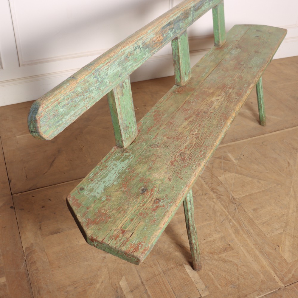 A long rustic wooden bench featuring distressed green paintwork, a simple narrow backrest, and four splayed legs. View V