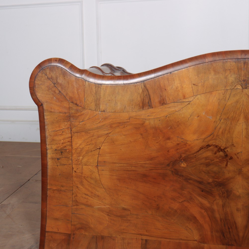 An 18th-century walnut serpentine commode featuring three long drawers with ornate brass handles and keyhole escutcheons, standing on turned bun feet. View IX