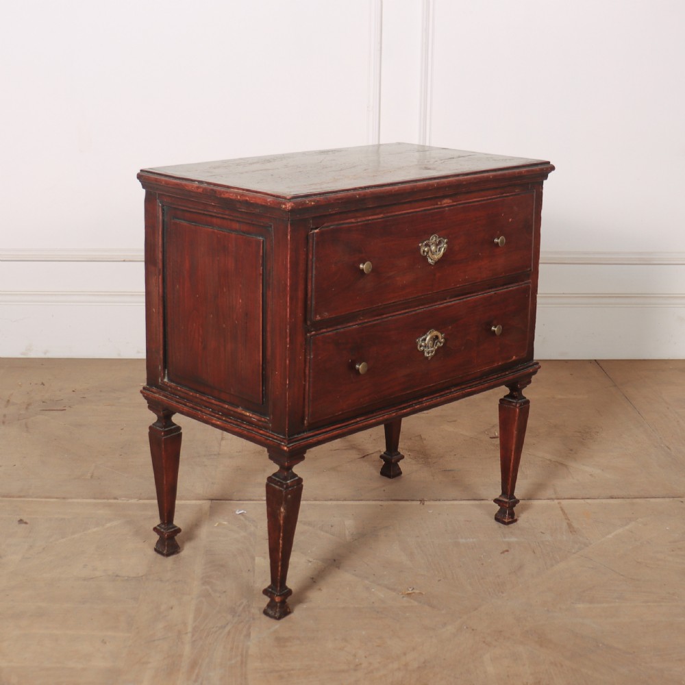 An 18th-century Italian walnut commode with two drawers, raised on tapered square legs with decorative brass fittings.