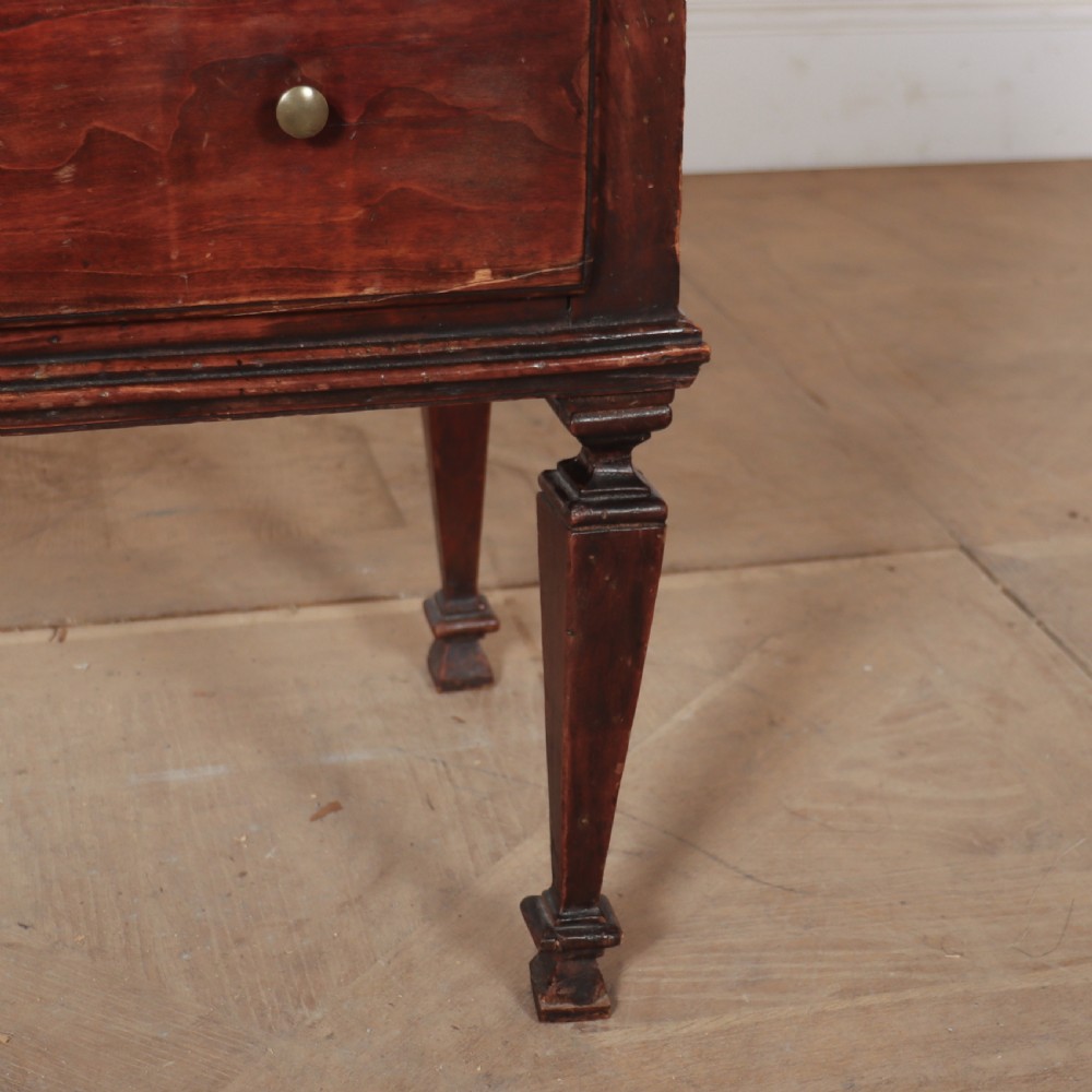 An 18th-century Italian walnut commode with two drawers, raised on tapered square legs with decorative brass fittings. View V