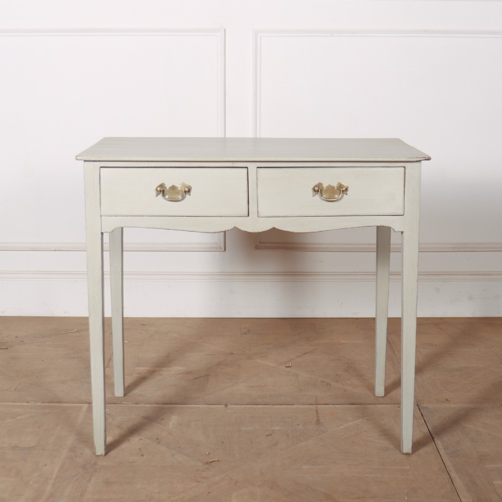 A light grey painted wooden side table featuring two small drawers with brass handles and straight tapered legs against a neutral background.