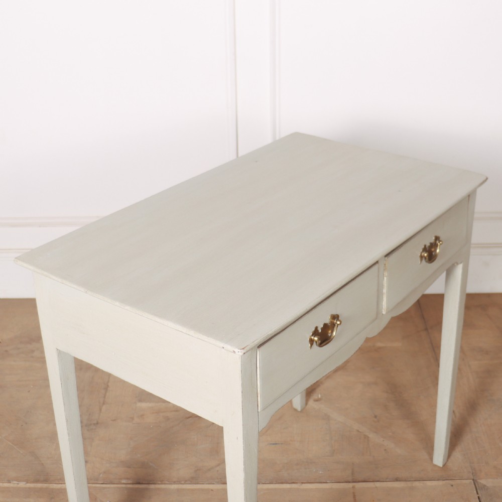 A light grey painted wooden side table featuring two small drawers with brass handles and straight tapered legs against a neutral background. View III