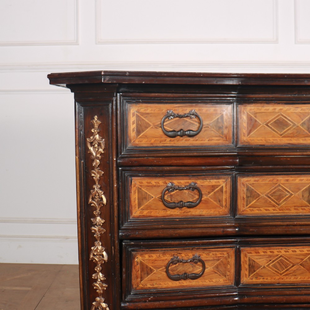 An 18th-century Italian walnut commode featuring four drawers with geometric parquetry inlay and gilt brass pilaster mounts. View II