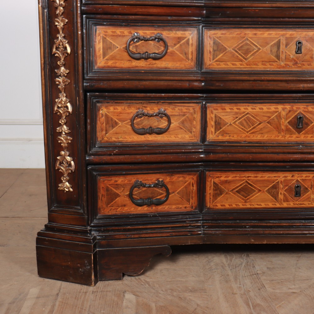 An 18th-century Italian walnut commode featuring four drawers with geometric parquetry inlay and gilt brass pilaster mounts. View III