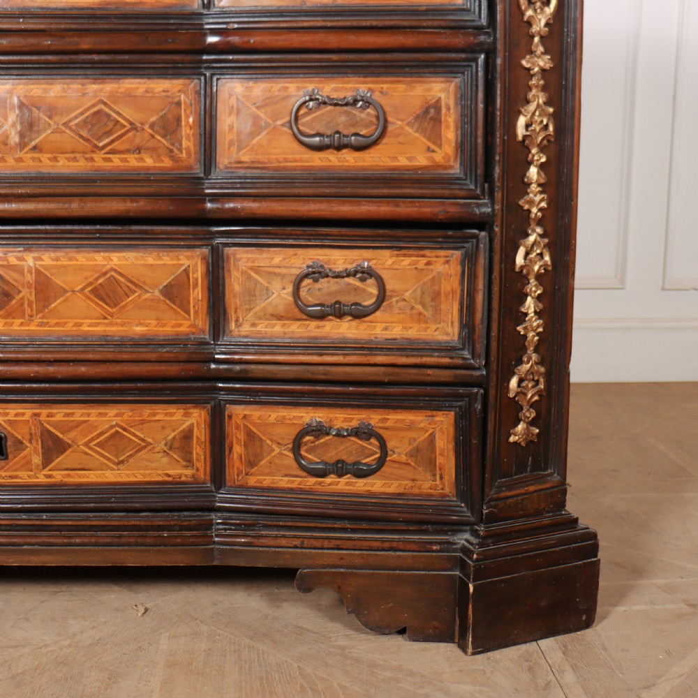 An 18th-century Italian walnut commode featuring four drawers with geometric parquetry inlay and gilt brass pilaster mounts. View VI