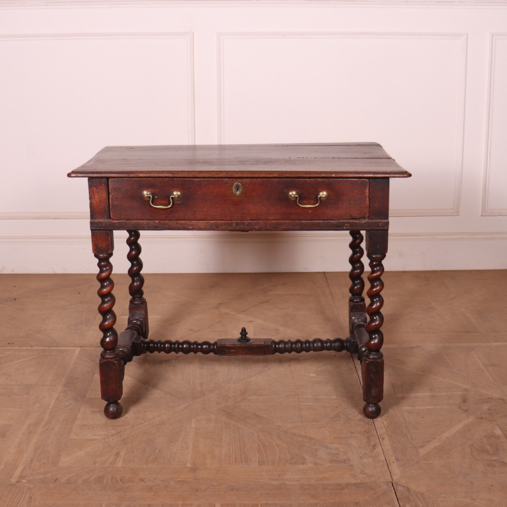 An antique dark oak side table with spiralled barley twist legs, an H-stretcher base, and a single frieze drawer with brass handles. View II
