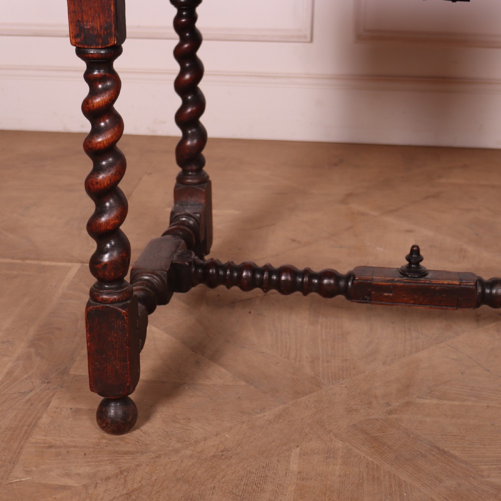 An antique dark oak side table with spiralled barley twist legs, an H-stretcher base, and a single frieze drawer with brass handles. View IV
