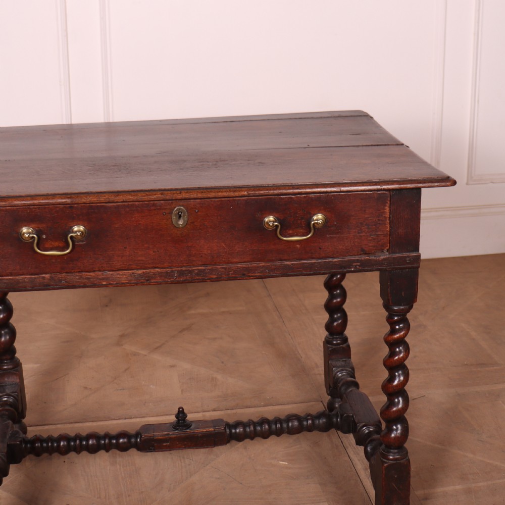 An antique dark oak side table with spiralled barley twist legs, an H-stretcher base, and a single frieze drawer with brass handles. View V
