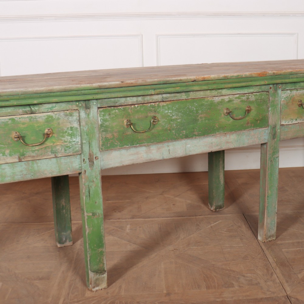 An exceptionally long antique English pine dresser base featuring a distressed green painted finish, four drawers with drop handles, and an unpainted timber top surface. View III
