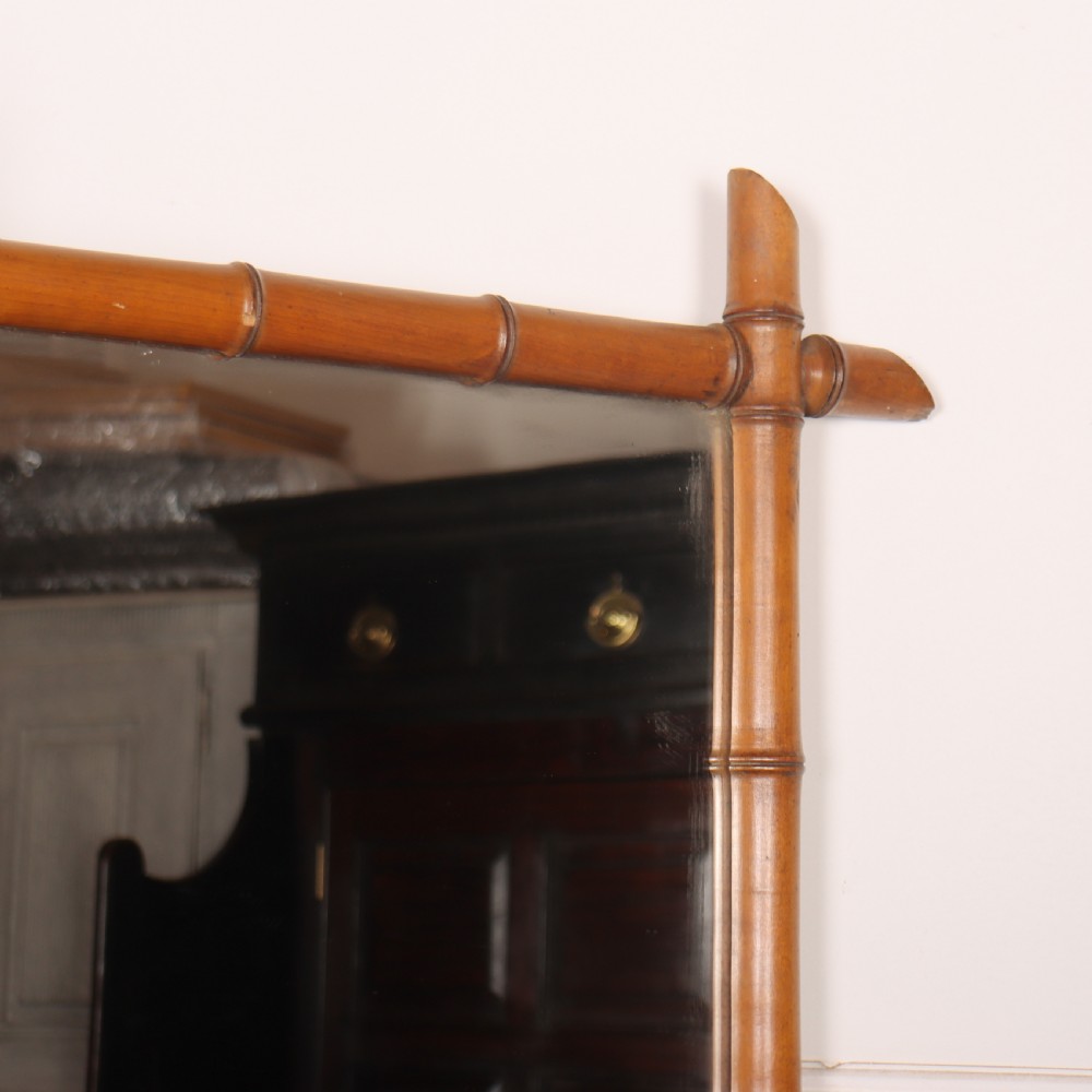 A rectangular wall mirror with a carved wooden frame styled to imitate bamboo, featuring crossed corner joints and a polished honey brown finish. View II