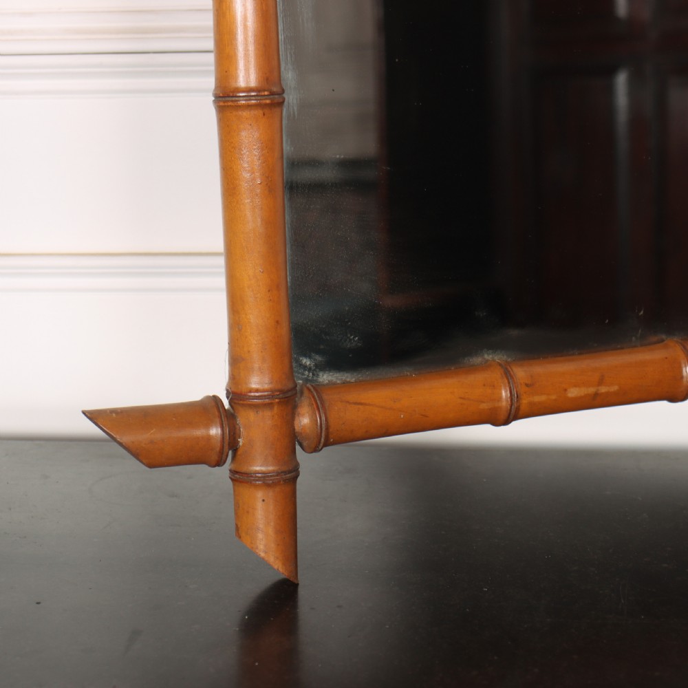 A rectangular wall mirror with a carved wooden frame styled to imitate bamboo, featuring crossed corner joints and a polished honey brown finish. View IV