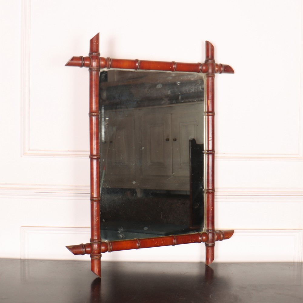 A rectangular French wall mirror featuring a carved wooden frame crafted to imitate bamboo with crossed, protruding corner joints.