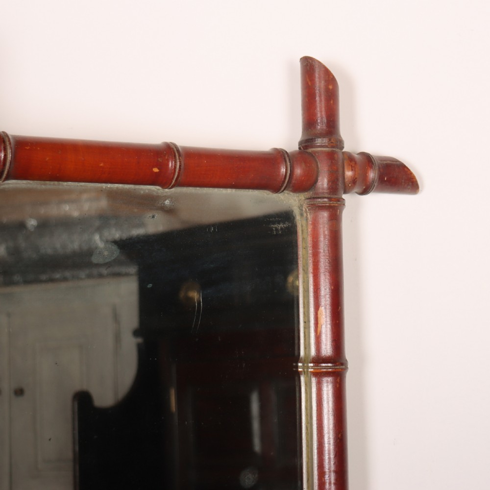 A rectangular French wall mirror featuring a carved wooden frame crafted to imitate bamboo with crossed, protruding corner joints. View III