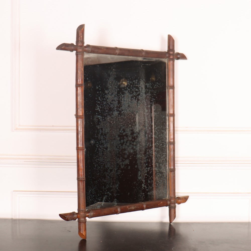 A rectangular antique French wall mirror featuring a carved wooden frame styled to resemble bamboo stems with protruding corner joints and distressed glass.