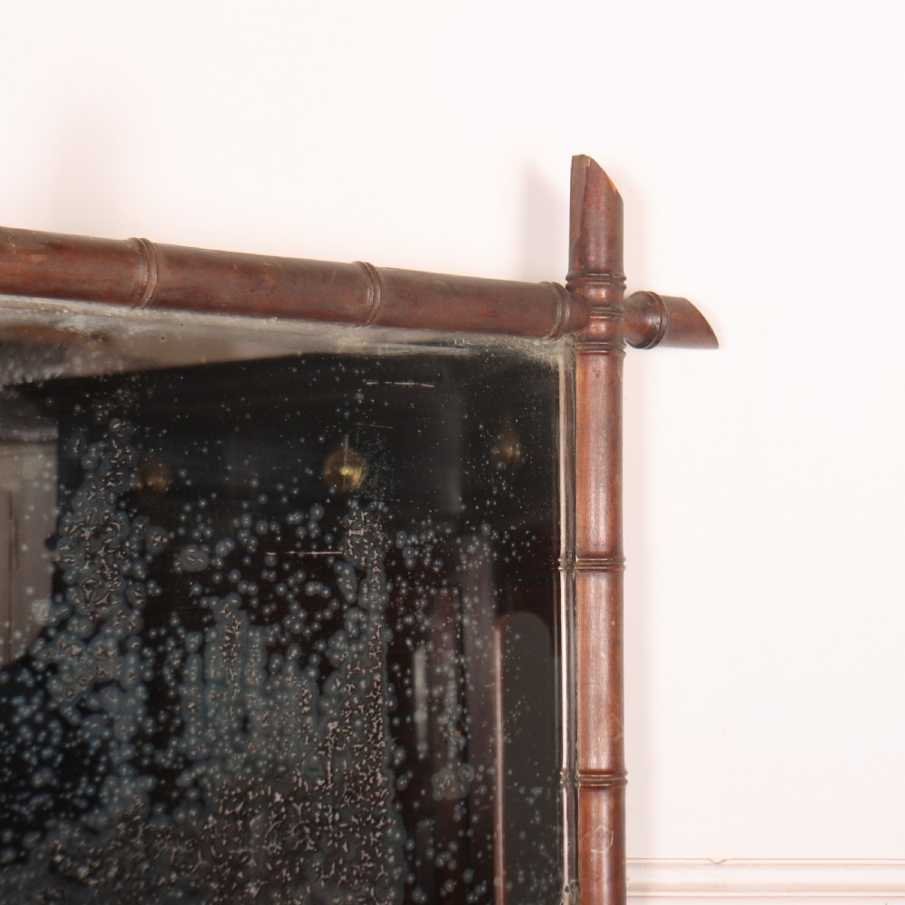 A rectangular antique French wall mirror featuring a carved wooden frame styled to resemble bamboo stems with protruding corner joints and distressed glass. View III