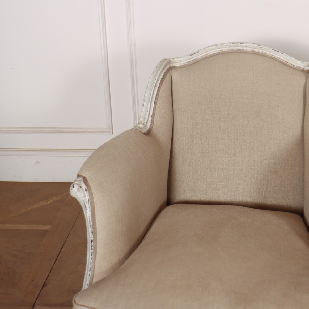 A pair of Swedish Gustavian style armchairs featuring distressed white painted carved wooden frames and beige linen upholstery. View III