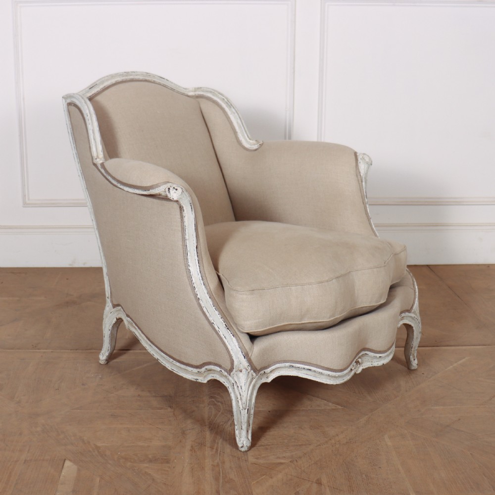 A pair of Swedish Gustavian style armchairs featuring distressed white painted carved wooden frames and beige linen upholstery. View IV
