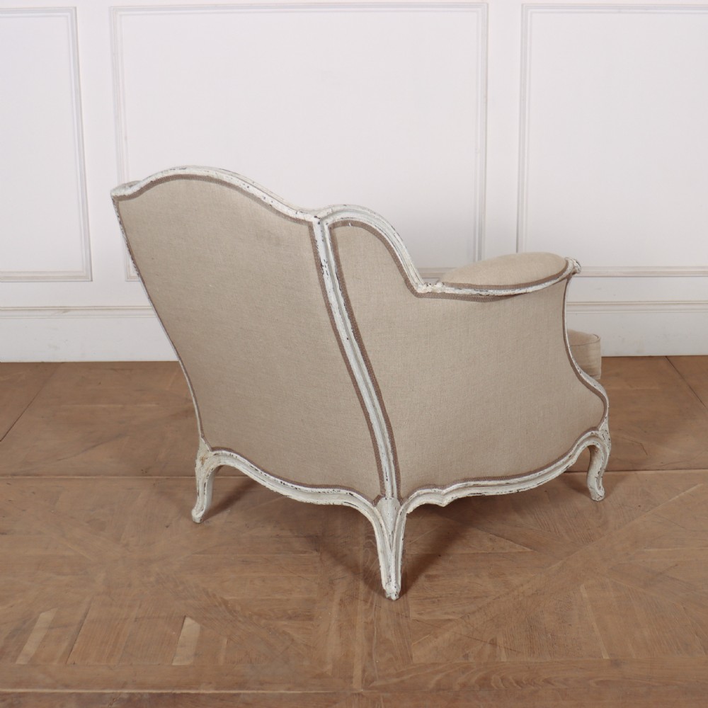 A pair of Swedish Gustavian style armchairs featuring distressed white painted carved wooden frames and beige linen upholstery. View V