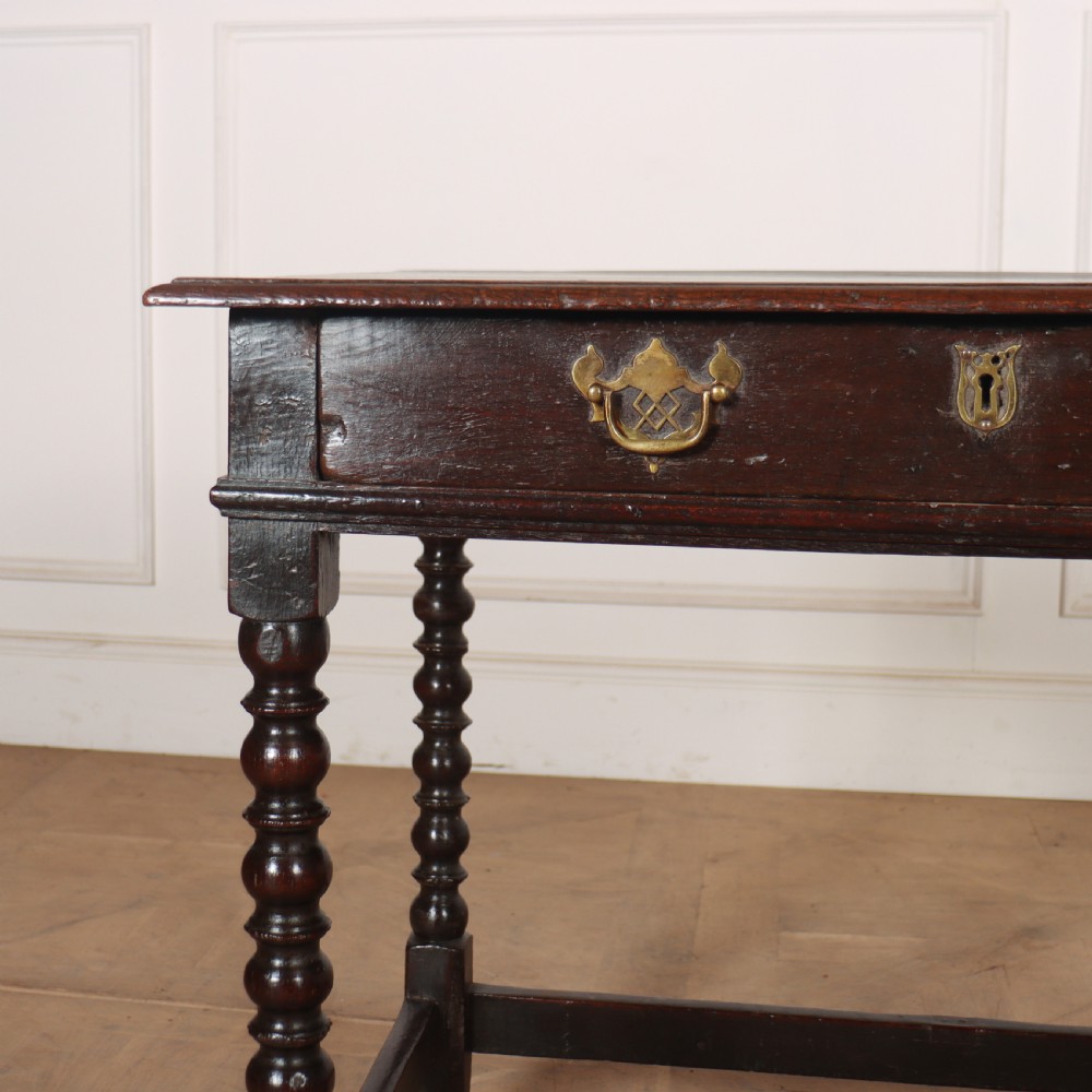 An 18th-century dark oak side table featuring a rectangular top, single drawer with brass handles, bobbin turned legs, and a box stretcher base. View III