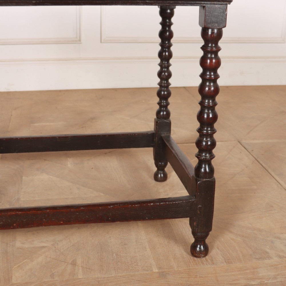 An 18th-century dark oak side table featuring a rectangular top, single drawer with brass handles, bobbin turned legs, and a box stretcher base. View IV